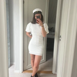 Vit kort klänning med puffärmar och knyt i ryggen - Superfin vit kort klänning med puffärmar och snygg knytning i ryggen. Klänningen har struktur i tyget och en figurnära passform. Perfekt till student eller sommaren!🌸 Helt ny med lappen kvar, köpt från en annan på plick som inte heller använt den. Säljer då jag ska ha en annan på studenten!🤍 
