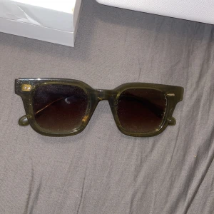 Mörkgröna solglasögon från CHIMI - Snygga solglasögon från CHIMI (04 green) i en mörkgrön, transparent plast med fyrkantig form och mörka glas. Perfekt accessoar för att lyfta din stil. Kommer med originalförpackning och fodral.