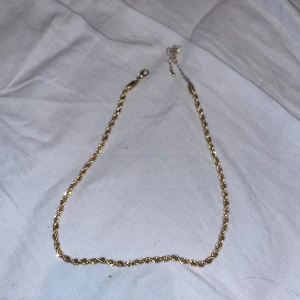 Rostfritt Guld halsband  - Säljer ett snyggt guldfärgat halsband med tvinnad kedja. Perfekt för dig som vill ha en stilren och trendig accessoar som sticker ut lite extra. Justerbar längd med liten kedja och lås baktill.