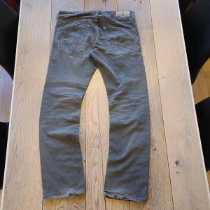 Grå jeans från Replay - Säljer ett par grå jeansbyxor från Replay i klassisk rak modell. Byxorna har fem fickor, dragkedja och knapp i midjan samt Replay-märke på bakfickan. Midjemått W31 och längd L32.