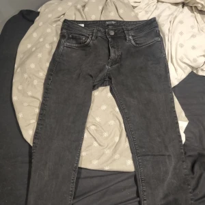 Svarta slim fit jeans från Jack & Jones - Säljer ett par svarta slim fit jeans från Jack & Jones, modell Glenn. Jeansen har klassisk femficksdesign, knappgylf och smal passform. Perfekta för dig som gillar en stilren och enkel look.