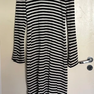 Stickad klänning  - Lång stickad klänning från Gina Tricot Snygg och bekväm långärmad klänning i svartvitt randigt mönster. Stickad kvalitet som sitter fint på kroppen. Perfekt för både vardag och kväll – matcha med sneakers eller boots!                                                           Använd en gång, djur och rökfritt 