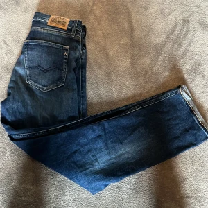 Blå jeansbyxor från Replay Thad - Säljer ett par klassiska blå jeansbyxor från Replay, modell Thad. Jeansen har raka ben, fem fickor och tydliga sömmar. Bakfickorna har Replay-logga och byxorna har en snygg tvättad look. Lite stora i storleken. Storlek 14 år eller 158. Men skulle säga att de passar lite större.