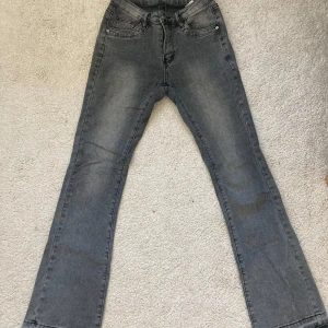 Grå jeans med bootcut - Säljer ett par grå jeans med bootcut-modell. Byxorna har klassisk femficksdesign och är tillverkade i en stretchig bomullsblandning för extra komfort. Perfekta för dig som gillar en tidlös look med lite vidare ben.