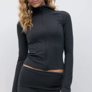 Mörkgrå tight träningsjacka med dragkedja - Säljer en mörkgrå, tight träningsjacka med hög krage och hel dragkedja framtill. Jackan har långa ärmar och är tight i modellen.💗