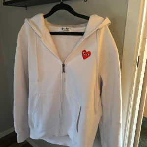 Comme des Garçons PLAY Zip - En riktig snygg cdg zip som är i ett fint skick, den är tyvärr lite för liten för mig och därav vill jag sälja den. Passar dig bäst om du är runt 180cm .  Bara att skriva om du undrar något eller om du vill ha bild på hur den sitter på 👍💫 priset är inte hugget i sten.