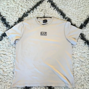 Beige Emporio Armani T-shirt - Säljer en stilren beige t-shirt från EA7 med logga på bröstet. Perfekt för en avslappnad look. Passar bra till både jeans och shorts.