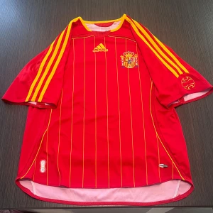 Äkta Spanien fotbollströja adidas - Säljer min otroligt snygga äkta Spanien tröja vintage! Tröjan är i storlek 13-14 år( 164cm) adidas! Den är i fint skick och perfekt nu inför sommaren! Hör av dig vid minsta lilla fundering! Kolla gärna in mina andra artiklar!  Fotboll fotbollströja football shirt adidas spain Spanien Nike fotbollsskor grisch sommar