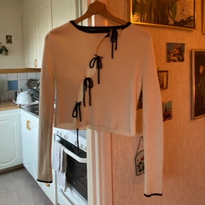 Vit ribbad tröja från ASOS DESIGN - Säljer en stilren vit ribbad tröja från ASOS DESIGN med svarta detaljer. Tröjan har långa ärmar och knytband framtill som ger en unik look. 