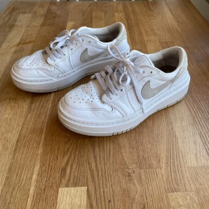 Vita Nike Air Jordan Elevate Low sneakers - Snygga vita Nike Air sneakers med klassisk design och perforerade detaljer för extra ventilation. Skorna har en stilren vit färg med ljusgrå detaljer och snörning framtill. Perfekta för en avslappnad stil.