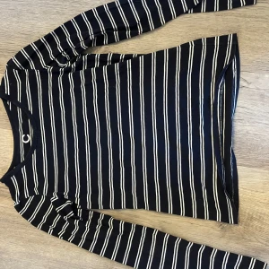 Svart och vit randig långärmad tröja - Säljer en svart och vit randig långärmad tröja från märket C. Tröjan är tillverkad i ekologisk bomull och har en klassisk rund halsringning. Perfekt för en stilren och bekväm look.