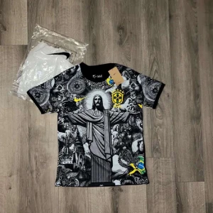 Svart och grå fotbollströja med tryck - Snygg fotbollströja från Nike med ett unikt svart och grått mönster och detaljer i gult. Tröjan har ett stort tryck av Kristusstatyn och andra konstnärliga element. 