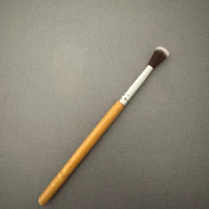 Sminkborste med trähandtag - En sminkborste med ett elegant trähandtag och mjuka, täta borst. Perfekt för att applicera ögonskugga eller blanda ut kanter för en jämn finish. Borsten har en metallisk fäste som håller borsten säkert på plats.