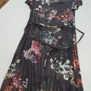 Blommig klänning från Ida Sjöstedt - Säljer en vacker blommig klänning från Ida Sjöstedt i 100% viskos. Klänningen har korta ärmar och ett bälte i midjan för en smickrande passform. Perfekt för sommarens alla tillfällen! 🌸