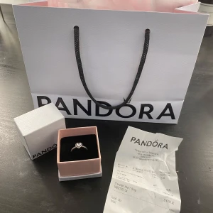 Elevated Heart Ring från Pandora - Säljer en vacker ring från Pandora med ett hjärtformat motiv och glittriga stenar. Ringen är i silver och har en elegant design som passar perfekt för speciella tillfällen.