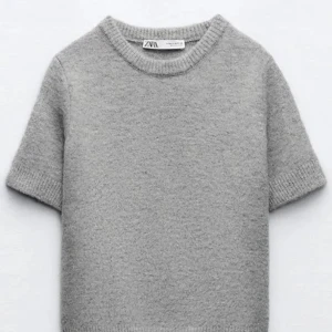 Grå stickad tröja från Zara - Säljer en mysig grå stickad tröja från Zara. Tröjan har korta ärmar och en rund halsringning. Enkel och stilren design som passar till det mesta. 