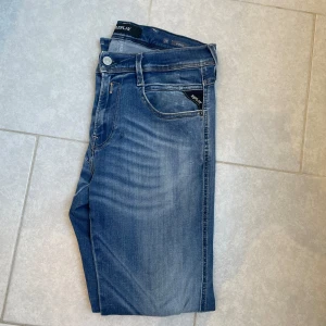 Blå jeans från Replay - Snygga blå jeans från Replay med en klassisk femficksdesign och snygga slitningar. De har en lagning, men inget som syns när man använder de! W29 L30