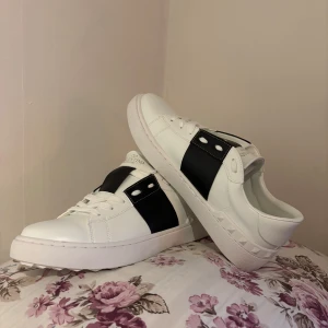 Valentino open - Snygga vita sneakers med svart detalj från Valentino. Skorna har en klassisk design med snörning och en stilren look. Perfekta för en trendig och avslappnad stil. Använda en gång därav riktigt bra skick! Sulan lite smutsig bara enda tecknet på användning!