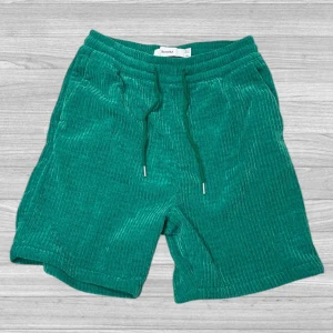 Bershka shorts - Snygga gröna manchester shorts från Bershka med bekväm passform. De har snörning i midjan för justerbarhet och en stilren look. Perfekta för en avslappnad stil.