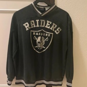 Tjocktröja - Cool svart sweatshirt med Raiders-logga på framsidan. Tröjan har långa ärmar och ribbade muddar vid ärmslut och nederkant. Perfekt för sportfantasten! 