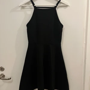 Svart klänning från H&M - Snygg svart klänning från H&M med smala axelband och en elegant, enkel design. Klänningen har en kort längd och är tillverkad i ett bekvämt material.