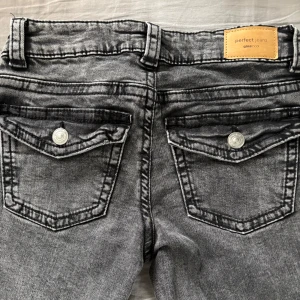 Grå jeans från Gina Tricot - Snygga grå jeans från Gina Tricot, modell Perfect Jeans. De är bootcut. Med medel låg midja. Använda nån gång.