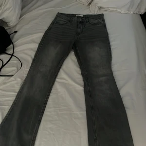 Grå bootcut jeans från Perfect Jeans - Snygga grå jeans från Perfect Jeans i storlek 36. Modellen har bootcut-ben och klassisk femficksdesign. Jeansen har en mörkgrå tvätt med lätt slitning och är tillverkade i mjukt denim-material. Perfekt för dig som gillar en avslappnad men trendig look. 