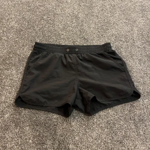 Svarta träningsshorts Pro Touch - Svarta träningsshorts från Pro Touch i lätt polyester. De har elastisk midja med snörning och två sidofickor. Perfekta för dig som vill ha bekväma och smidiga shorts till träning eller sport. Klassisk och enkel design som funkar till det mesta. SUPER sköna!😍