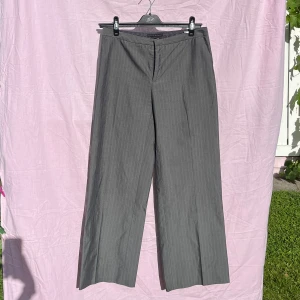 Grå kostymbyxor från Zara Basic - Snygga grå kostymbyxor från Zara Basic med diskreta ränder och klassisk rak passform. Byxorna har fickor i sidorna och stängs med dragkedja fram. Materialet är en blandning av ull och polyester, vilket ger en mjuk och stilren känsla. Perfekta för en clean och dressad look.