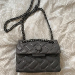 Grå axelväska från Kurt Geiger - Intressekoll på min gråa Kurt Gegier väska. Lite slitningar som syns på bilderna men inget man tänker på. Hittar tyvärr inte dustbagen. Skriv för flera bilder eller andra frågor. 💕