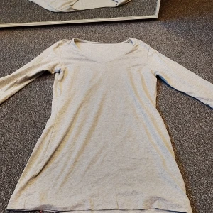 Ljusgrå långärmadtröja Esmara - En enkel och stilren ljusgrå långärmadtröja från Esmara i storlek M. Tröjan är lång ärmat, v-ringad hals och är tillverkad i mjuk bomull. Passformen är normal och modellen är rak med en klassisk look som funkar till många olika stilar.