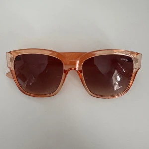 Orange solglasögon från Prestige - Snygga solglasögon från Prestige med transparent båge och stora fyrkantiga linser i brun toning. Perfekt accessoar för att sticka ut och ge din look en cool vibe. Lätta och bekväma att bära hela dagen.