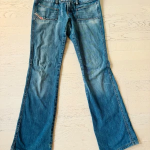 Replay bootcut jeans med slitna detaljer - Säljer ett par blå Disel  jeans med bootcut passform och slitna detaljer vid bensluten. Jeansen har två framfickor med Replay-logga, två bakfickor och klassisk knappstängning. Materialet är jeans med en snygg tvättad look och ljusare partier. De sprack under dragkedjan som man ser på en bild! Men har lagats av en skräddare🥰