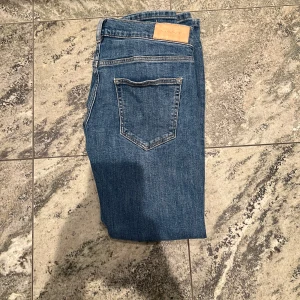 Blå jeans från GANT, straight fit - Snygga blå jeans från GANT med klassisk femficksdesign och rak passform. Jeansen har normal midja och är tillverkade i mjukt denimtyg med subtila slitningar. Perfekta för dig som gillar en clean och tidlös look. De är slim fit och passar typ 165-160