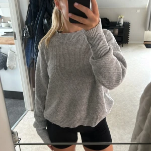 Grå stickad tröja med ribbad kant - Säljer en grå stickad tröja med ribbad struktur och breda muddar vid ärmslut och hals. Tröjan har en lös passform💕