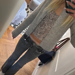 Grå bootcut jeans från Gina Tricot - Säljer ett par grå jeans från Gina Tricot med bootcut passform och låg midja. Jeansen har coola framfickor med lock och stora bakfickor, samt klassisk knapp och dragkedja. Materialet är jeans och färgen är mörkgrå med lite tvättad look.