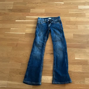 Blå bootcut jeans  - Snygga blå jeans från Gina Tricot i bootcut-modell med cool broderad detalj på bakfickorna. Jeansen har kontrastsömmar och klassisk femficksdesign. Perfekt för dig som vill ha en unik look. 