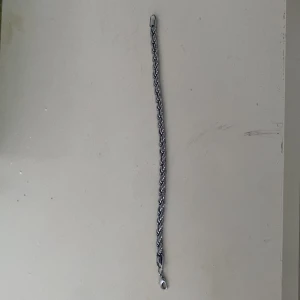 Flätat silverfärgat armband - Snyggt armband i silverfärg med flätad kedja och robust karbinlås. Perfekt för dig som gillar stilrena accessoarer med lite edge. Passar både till jeans och hoodie eller när du vill lyfta din outfit med något extra. Metallfinishen ger en cool vibe.