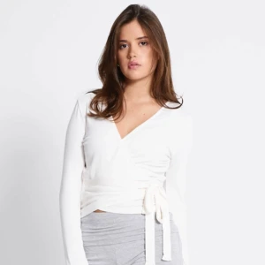 Vit omlottopp med knytband - Snygg vit omlottopp med långa ärmar och knytband i midjan. 