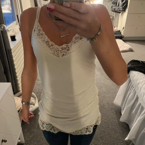 Vit spetslinnetopp  - Supersöt vit linnetopp från Gina Tricot i storlek XS. Toppen har tunna axelband, v-ringning och fina spetsdetaljer både vid halsringningen och nertill. Perfekt att styla med jeans eller kjol för en fräsch look.