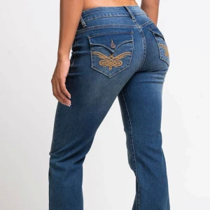 Blå bootcut jeans från Madlady storlek 34 tall - Säljer ett par blå jeans från Madlady i modellen bootcut med snygga broderade detaljer på bakfickorna. Jeansen har låg midja, klassisk femficksdesign och är tillverkade i jeansmaterial. Passformen är normal och benen är lätt utsvängda för en trendig look. Ordinare pris är 800kr