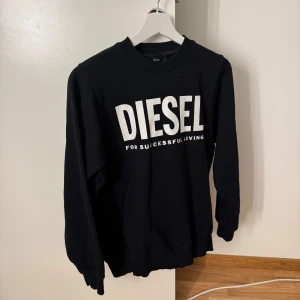 Svart sweatshirt från Diesel XS - Svart sweatshirt från Diesel i storlek XS med stor vit logotyp på bröstet. Tröjan har rund hals, långa ärmar och är gjord i mjuk bomull. Perfekt för dig som gillar streetwear och vill ha en enkel men snygg look.
