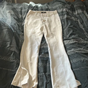 Vita kostymbyxor från BikBok - Snygga vita kostymbyxor från BikBok i klassisk modell med raka ben och pressveck. Byxorna har fickor fram, hällor för bälte och stängs med dragkedja och knapp. Perfekta för en clean och stilren look.