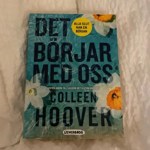 Det börjar med oss - Boken 'Det börjar med oss' av Colleen Hoover är en uppföljare till succén 'Det slutar med oss'. Omslaget är blått med blommor och texten 'Alla slut har en början'. Perfekt för dig som älskar romantiska och känslosamma berättelser.