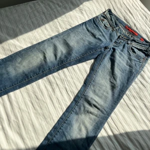Blå jeans från QS by Oliver  - Snygga vintage  jeans från QS by Oliver med klassisk femficksdesign och knappgylf. De har en lätt tvättad look och är bootcut. Använda fåtal gånger men är i jätte bra skick