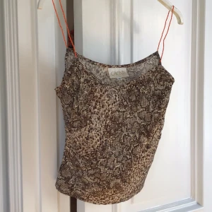 Mönstrad linnetopp från Cache - Säljer en snygg linnetopp från Cache med ett djurinspirerat mönster i bruna toner. Toppen har tunna axelband och en lös passform, perfekt för varma dagar. Passar bra till både jeans och kjol. 🐍