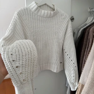 Vit stickad tröja från Hollister - Säljer en snygg vit stickad tröja från Hollister. Tröjan har en hög krage och långa ärmar med ett fint stickat mönster. Perfekt för kyliga dagar. 🧶