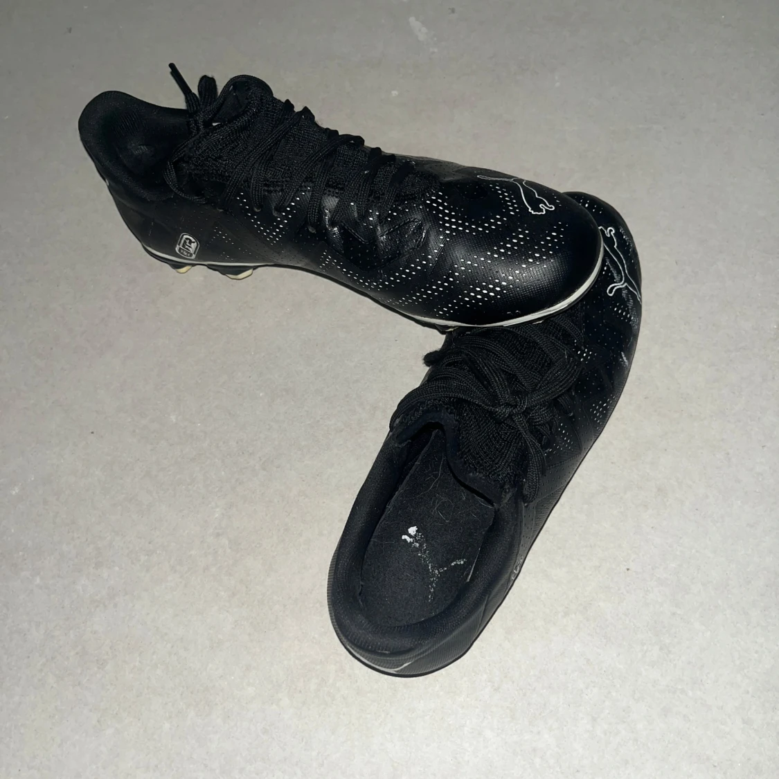 Svarta Puma fotbollsskor med vita detaljer