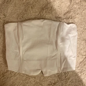 Vit tubtopp från NLY Trend - Säljer en stilren vit tubtopp från NLY Trend. Toppen har en smockad baksida för extra stretch och komfort. Perfekt för att matcha med olika outfits. Hör av dig vid intresse!