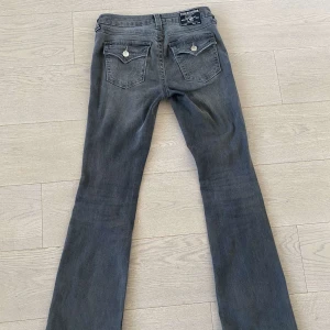 Grå bootcut jeans från true religon  - Snygga grå bootcut jeans från Becca med en midwaist passform. De har klassiska femficksdetaljer och en stilren design som passar perfekt till vardags. Tillverkade i Bangladesh.